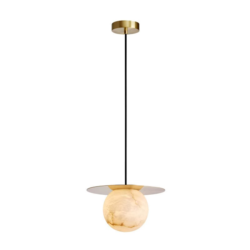 A modern pendant light featuring a round alabaster shade suspended from a sleek black cord and a minimalist gold ceiling mount.