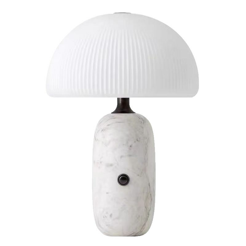 A modern lamp with a marble base and a white ribbed glass shade.
